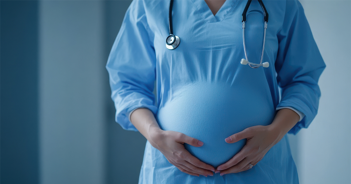schwangere Ärztin im blauen Kittel fasst sich um Babybauch